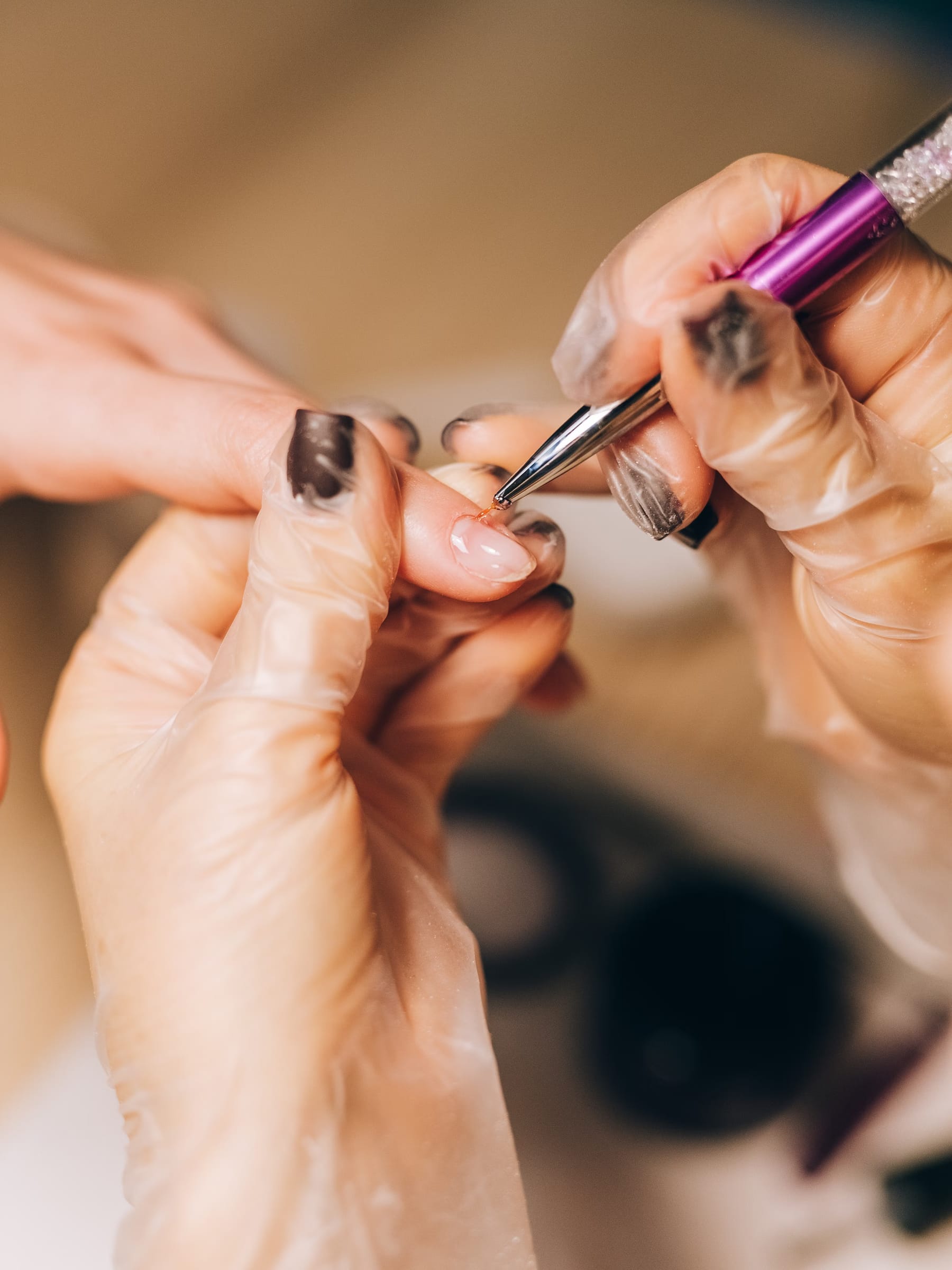Nail technician applying gel polish under a lamp