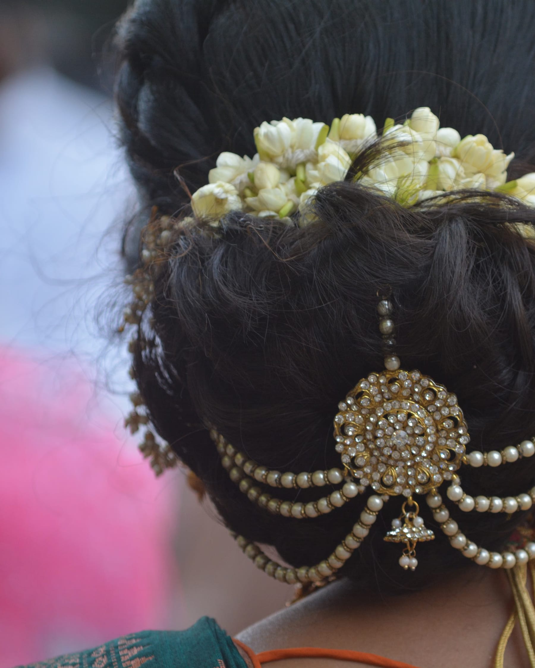 Bride in red lehenga with a low bun and fresh flowers, HD makeup finish